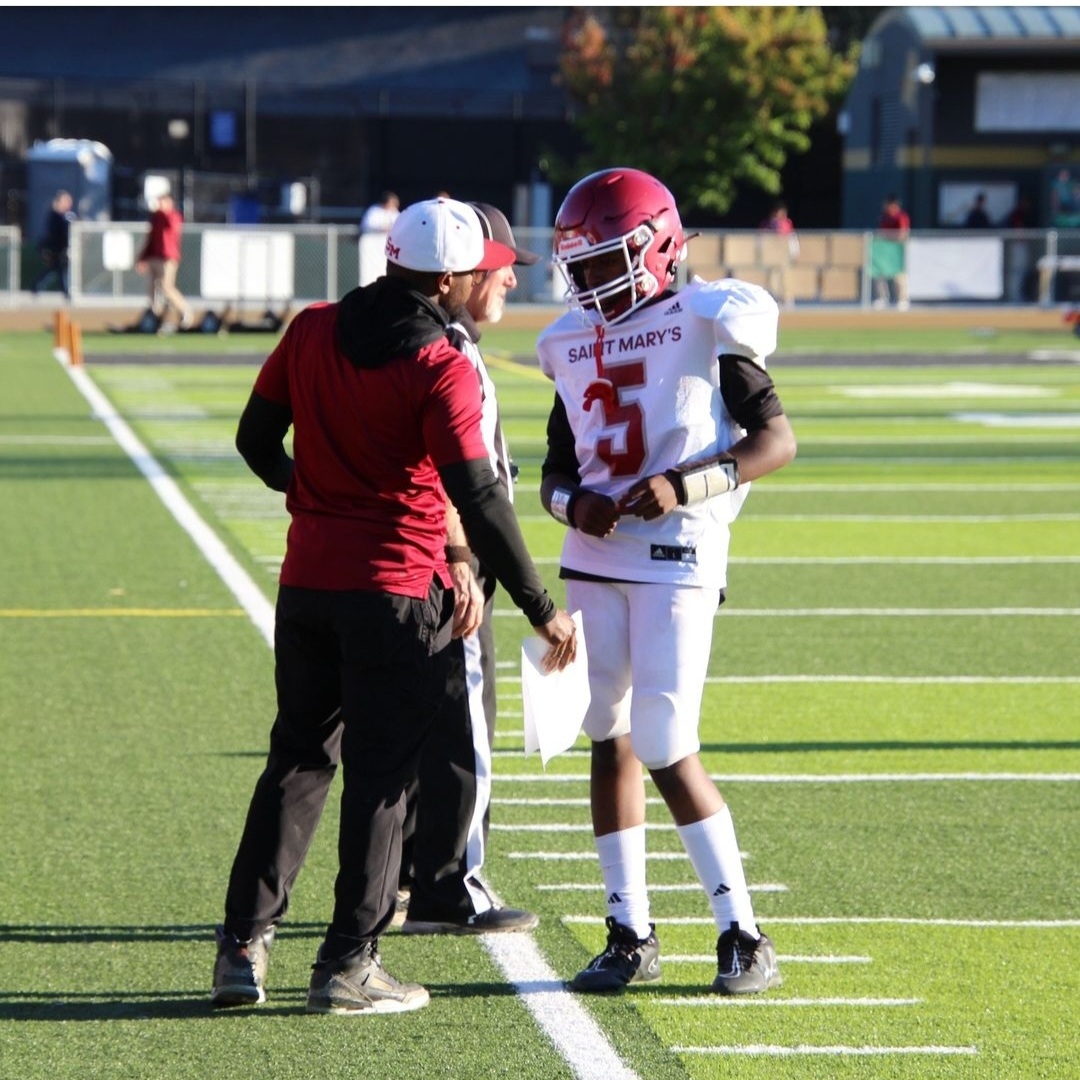 Marc coaching a young quarterback on the sideline during a game